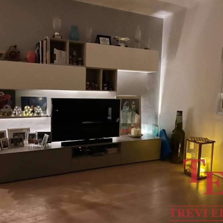 Современная гостиная с телевизором, декоративными элементами и теплым освещением для роскошной жизни.