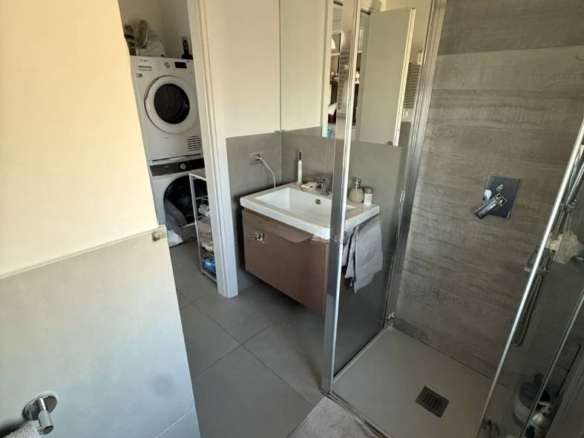 Современная ванная комната с душевой кабиной, стиральной машиной и аккуратным интерьером, создающая комфорт и уют в элитной недвижимости от Треви Элит.