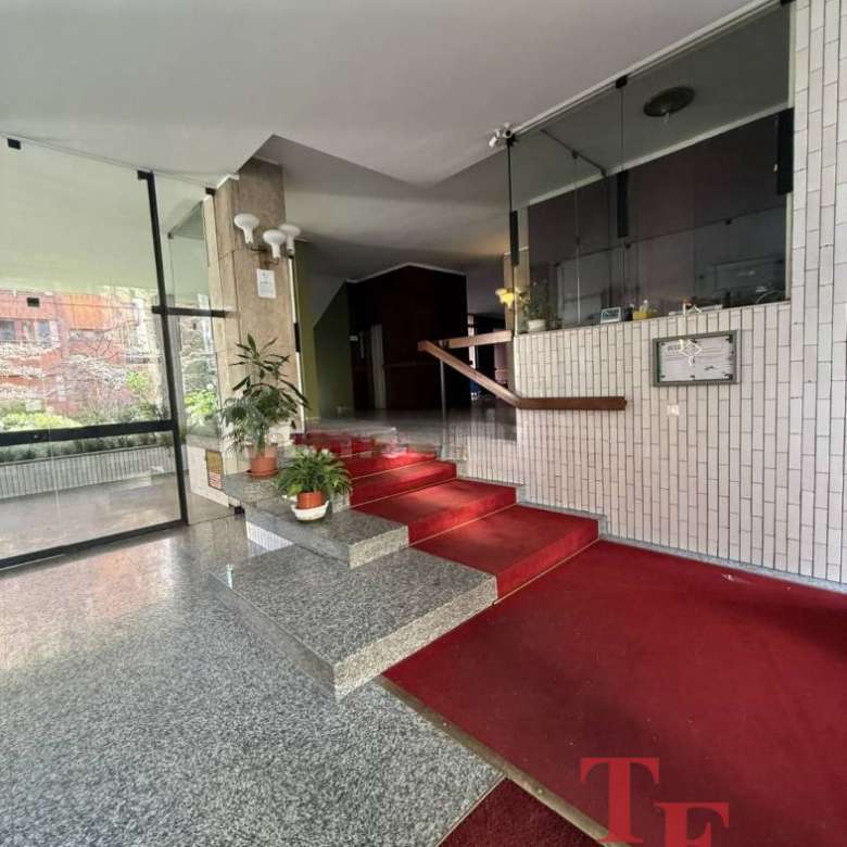 Современный вход в элитное офисное здание, интерьеры с мраморной отделкой, уютные растения и удобные ступени, идеально подходящий для клиентов агентства недвижимости.