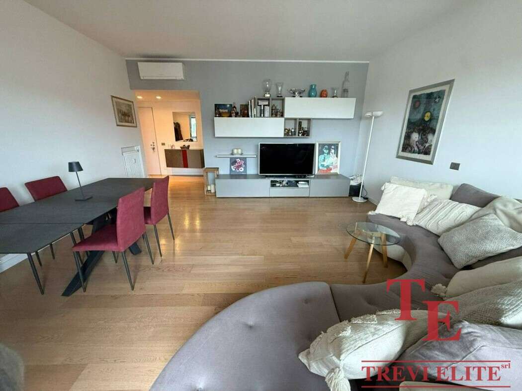 Современная гостиной с мягким диваном, телевизором и стильной мебелью, в интерьере преобладают светлые тона, что создает уютную атмосферу для комфортного отдыха.