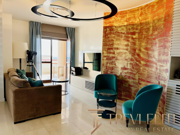 Современная гостиная с яркой декоративной стеной, уютным диваном, креслами и балконом, наполняющим пространство естественным светом. Идеальное место для отдыха и просмотра телевизора.