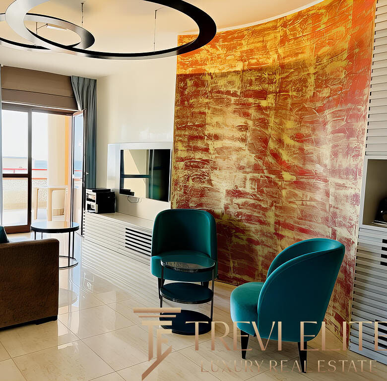 Современная гостиная с яркой декоративной стеной, уютным диваном, креслами и балконом, наполняющим пространство естественным светом. Идеальное место для отдыха и просмотра телевизора.