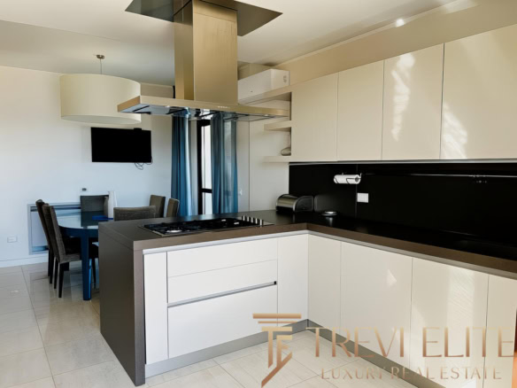 Современная уютная кухня в элитной квартире с светлыми фасадами и стильной черной столешницей. Чистый дизайн и функциональность, идеально для комфортной жизни.