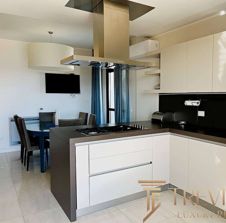 Современная уютная кухня в элитной квартире с светлыми фасадами и стильной черной столешницей. Чистый дизайн и функциональность, идеально для комфортной жизни.