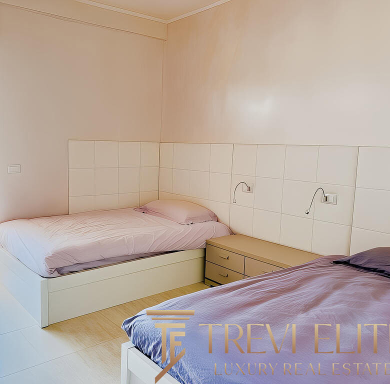 Комнатное изображение спальни с двумя кроватями и выходом на балкон, светлые стены и современный дизайн.