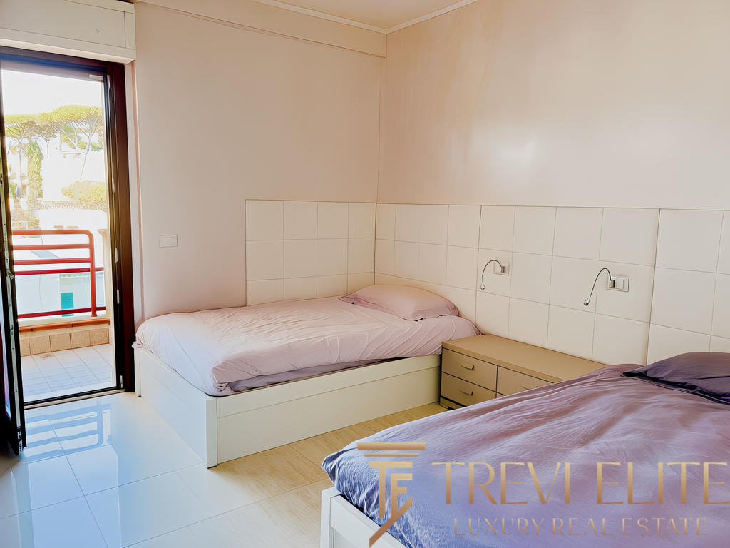 Комнатное изображение спальни с двумя кроватями и выходом на балкон, светлые стены и современный дизайн.