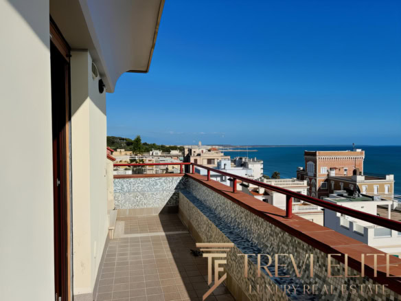 Обзор видового балкона с морским пейзажем на фоне современного жилого комплекса вдоль побережья.