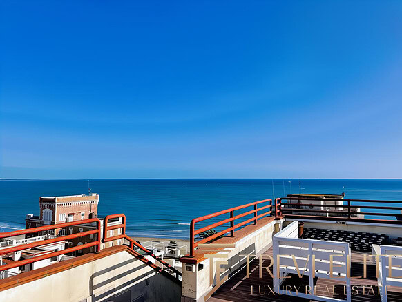 Вид на морской пейзаж с террасы на крыше современного жилого комплекса на берегу моря. Яркое солнечное небо, голубое море и уютная зона отдыха с комфортной мебелью.