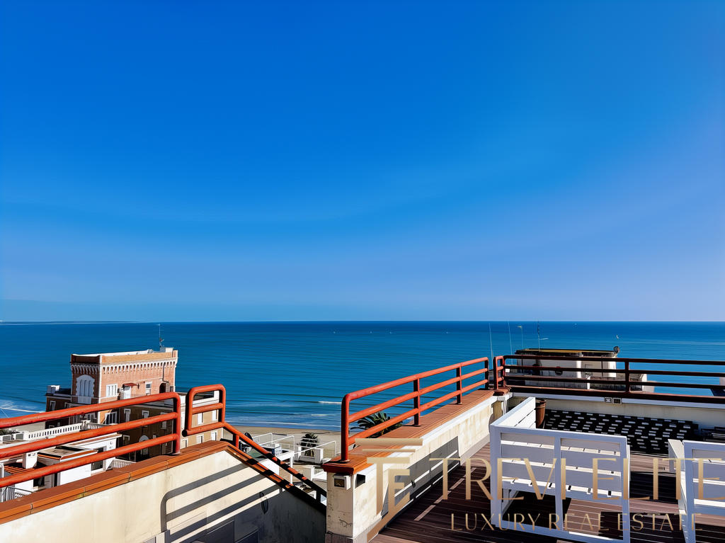 Вид на морской пейзаж с террасы на крыше современного жилого комплекса на берегу моря. Яркое солнечное небо, голубое море и уютная зона отдыха с комфортной мебелью.