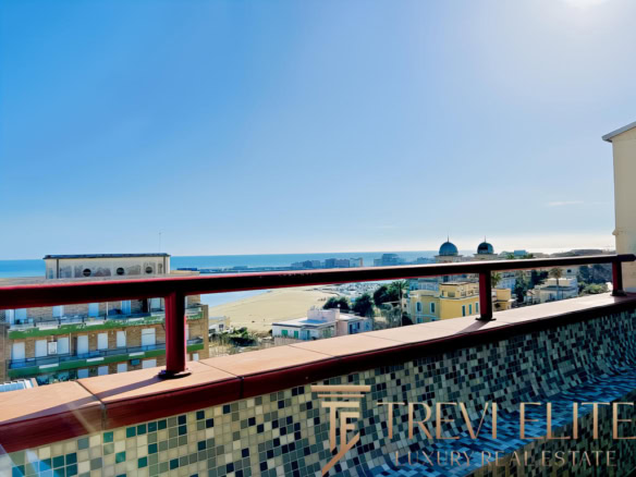 Вид на морской пейзаж с балкона на верхнем этаже, современные жилые дома и пляж, яркое солнечное небо, панорамный обзор на Черное море, архитектура элитных зданий.