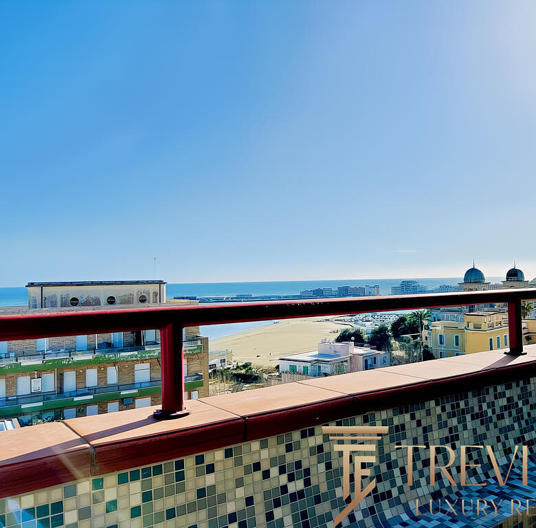 Вид на морской пейзаж с балкона на верхнем этаже, современные жилые дома и пляж, яркое солнечное небо, панорамный обзор на Черное море, архитектура элитных зданий.