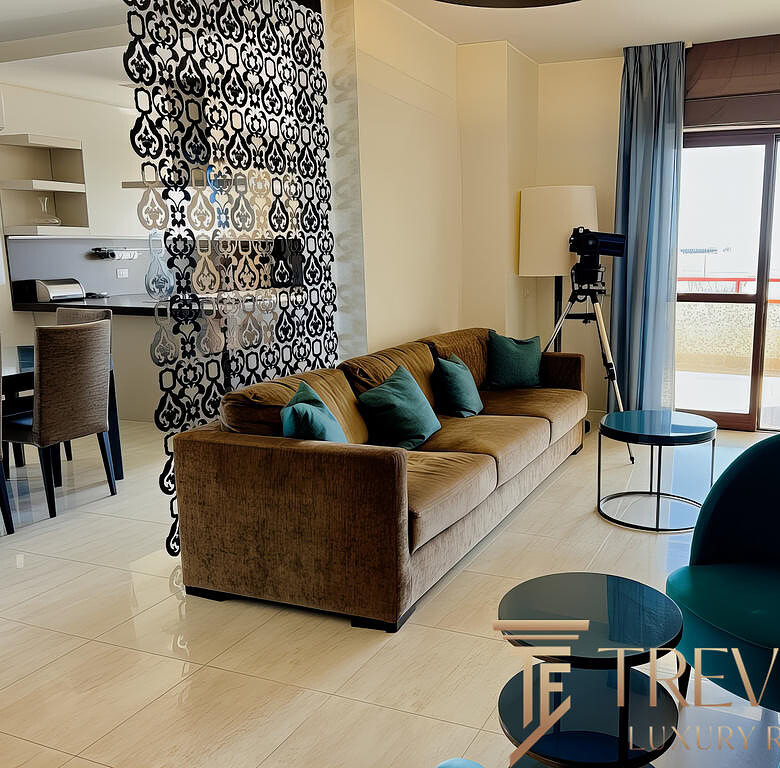 Квартира в современном стиле с уютной гостиной, видом на балкон, удобной мебелью и панорамным окном для светлых интерьеров.