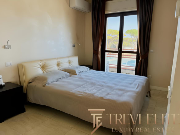 Уютная спальня с двуспальной кроватью, просторными окнами и видом на зелёные деревья, идеально подходит для комфортного отдыха и проживания в роскошном жилье от Треви Элит.