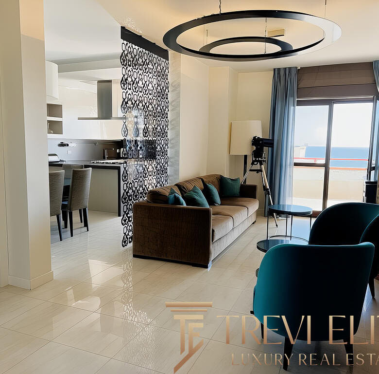 Современная гостиная с просторным балконом, панорамным видом на море, стильной мебелью и дизайнерским освещением в апартаментах Треви Элит.