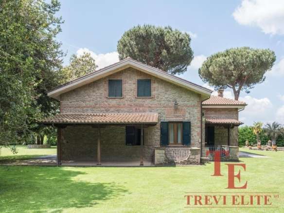 Элегантный каменный коттедж с зелёным газоном и ухоженным окружением на фоне голубого неба. Идеальный роскошный дом для проживания или инвестиций в недвижимости премиум-класса.