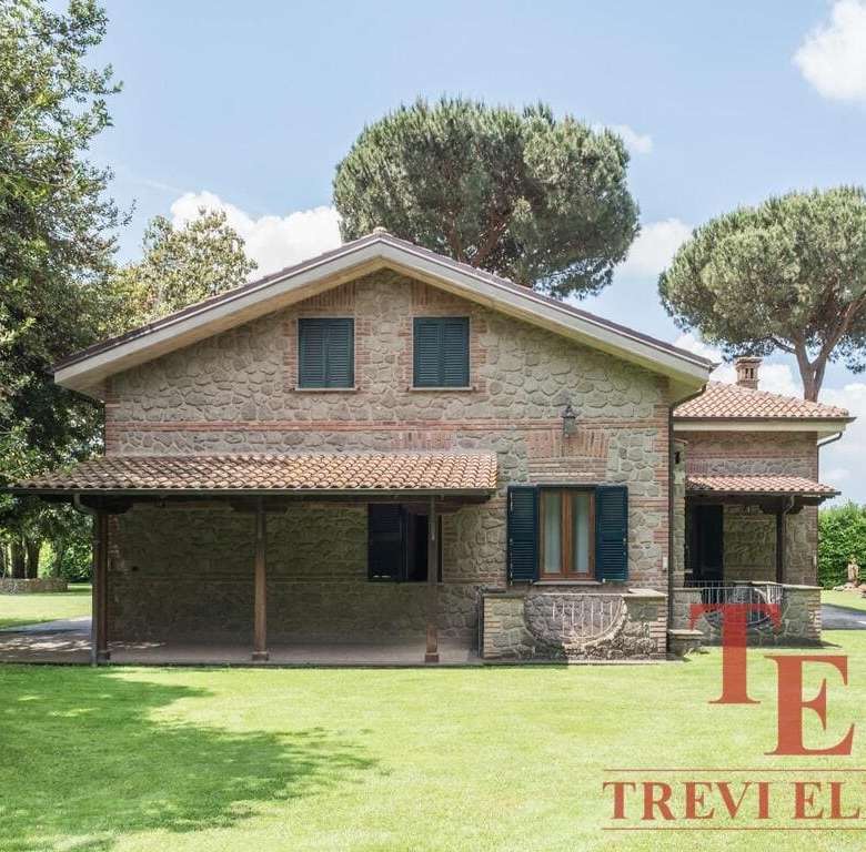 Элегантный каменный коттедж с зелёным газоном и ухоженным окружением на фоне голубого неба. Идеальный роскошный дом для проживания или инвестиций в недвижимости премиум-класса.