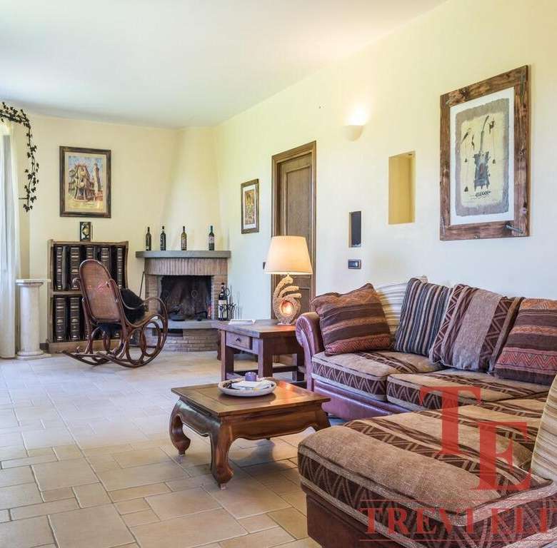 Уютная гостиная с камином, мягким диваном и стильными декоративными элементами, создающая атмосферу комфорта и роскоши в элитной недвижимости.