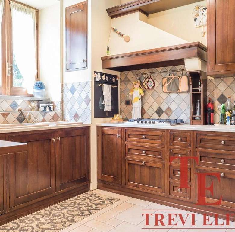 Уютная классическая кухня с деревянными фасадами, натуральным каменным фартуком и большим окном, пропускающим много естественного света. Идеально подходит для комфортного домашнего обеда.