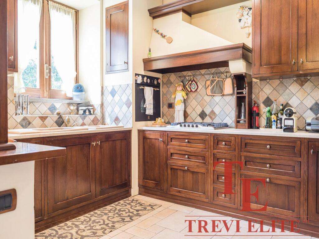 Уютная классическая кухня с деревянными фасадами, натуральным каменным фартуком и большим окном, пропускающим много естественного света. Идеально подходит для комфортного домашнего обеда.