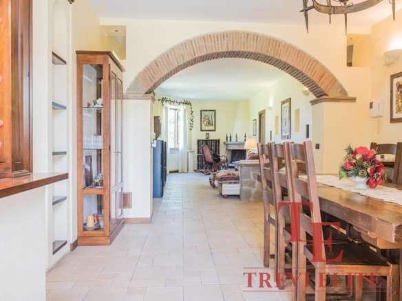 Внутренний дизайн просторной гостиной с обеденной зоной, аркой из кирпича, деревянной мебелью и уютной атмосферой, идеальной для элитных итальянских и зарубежных недвижимости.