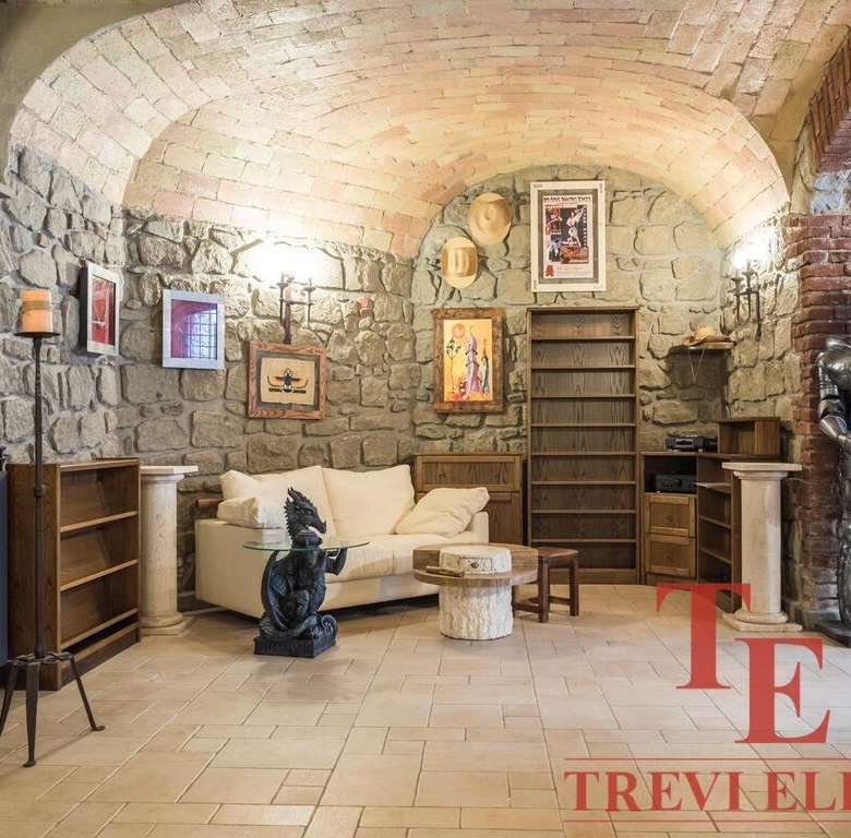 Красивая гостиная в стиле рустик с каменными стенами, арками и антикварной мебелью, украшенная картинами и скульптурами, создающая уютную атмосферу элитной недвижимости.