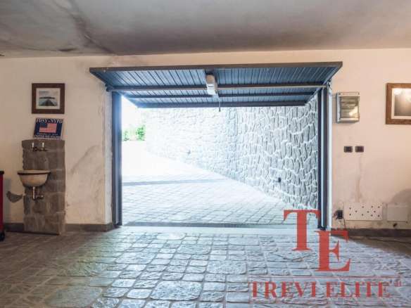 Элитное изображение гаража с открытым въездом, каменной отделкой и уютным интерьером, предоставляющее эксклюзивный доступ к высококлассной недвижимости.