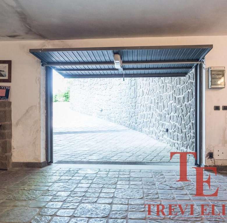 Элитное изображение гаража с открытым въездом, каменной отделкой и уютным интерьером, предоставляющее эксклюзивный доступ к высококлассной недвижимости.