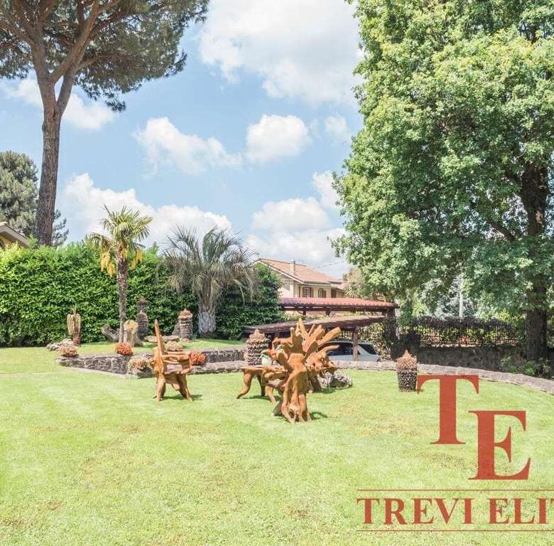 Тень, деревья и ухоженный газон в саду элитного виллы в Италии, окружённой натуральными растениями и декоративными элементами, создающие атмосферу уюта и роскоши.