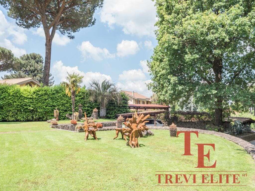 Тень, деревья и ухоженный газон в саду элитного виллы в Италии, окружённой натуральными растениями и декоративными элементами, создающие атмосферу уюта и роскоши.