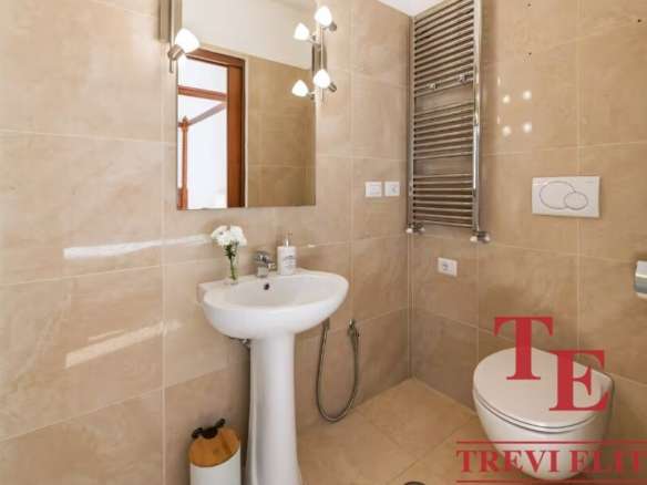 Роскошная современная ванная комната с просторным зеркалом, стилизованной сантехникой и теплым beige-оттенком стен. Идеально оборудована для комфортного проживания.