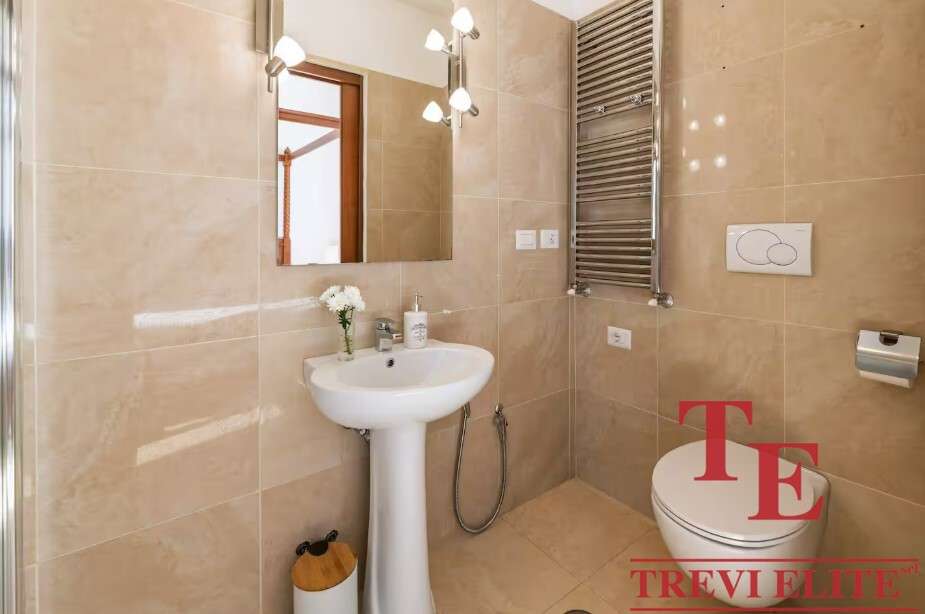 Роскошная современная ванная комната с просторным зеркалом, стилизованной сантехникой и теплым beige-оттенком стен. Идеально оборудована для комфортного проживания.