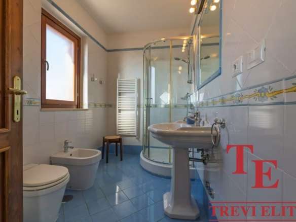 Элегантная современная ванная комната с душевой кабиной, умывальником и окном, обеспечивающим естественное освещение, стильное оформление и качественные материалы.