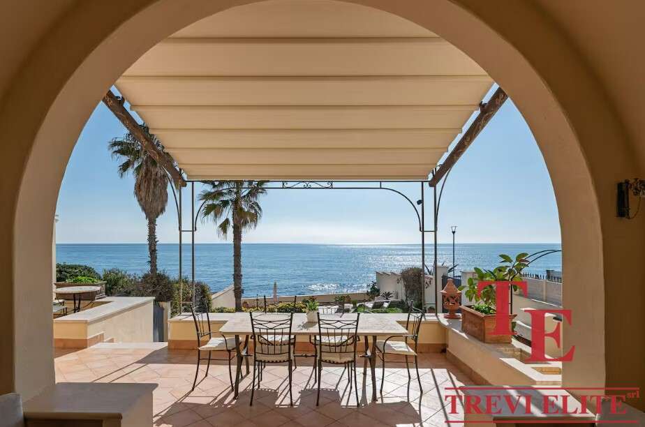 villa na more ryadom s rimom (21) Современная терраса с видом на море и пальмами у элитного итальянского дома. Роскошное пространство для отдыха с уютной тенью и живописным морским пейзажем.