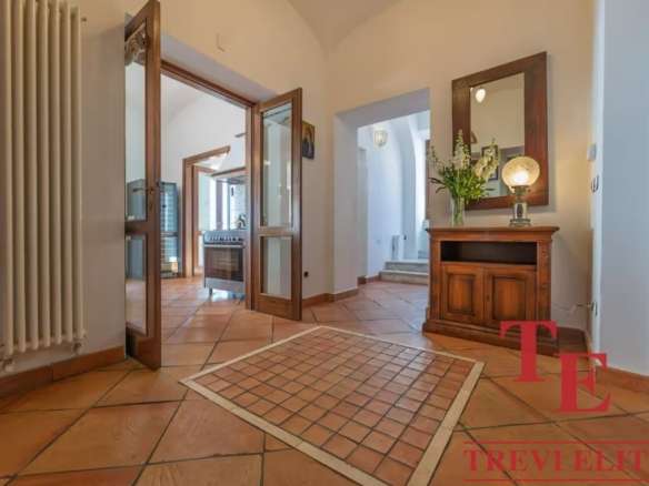 Элегантный интерьер входной зоны с деревянной мебелью и теплой подсветкой, создающий уютную атмосферу в роскошном доме. Идеальное сочетание комфортных и стильных элементов для высокого статуса.