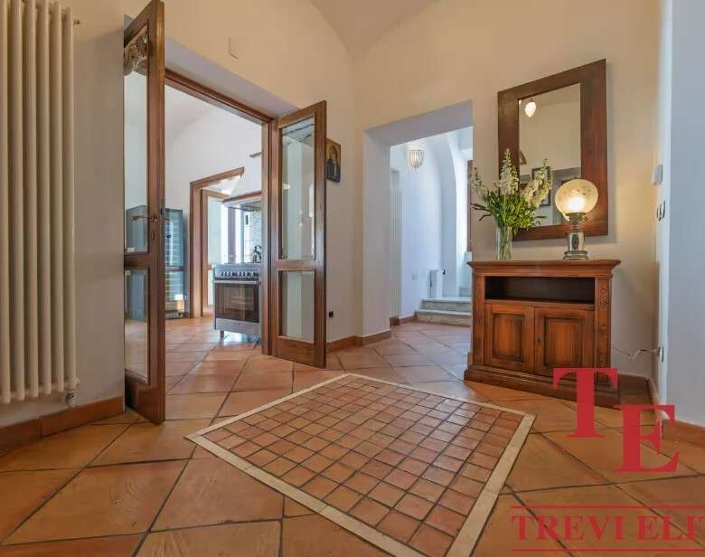 Элегантный интерьер входной зоны с деревянной мебелью и теплой подсветкой, создающий уютную атмосферу в роскошном доме. Идеальное сочетание комфортных и стильных элементов для высокого статуса.