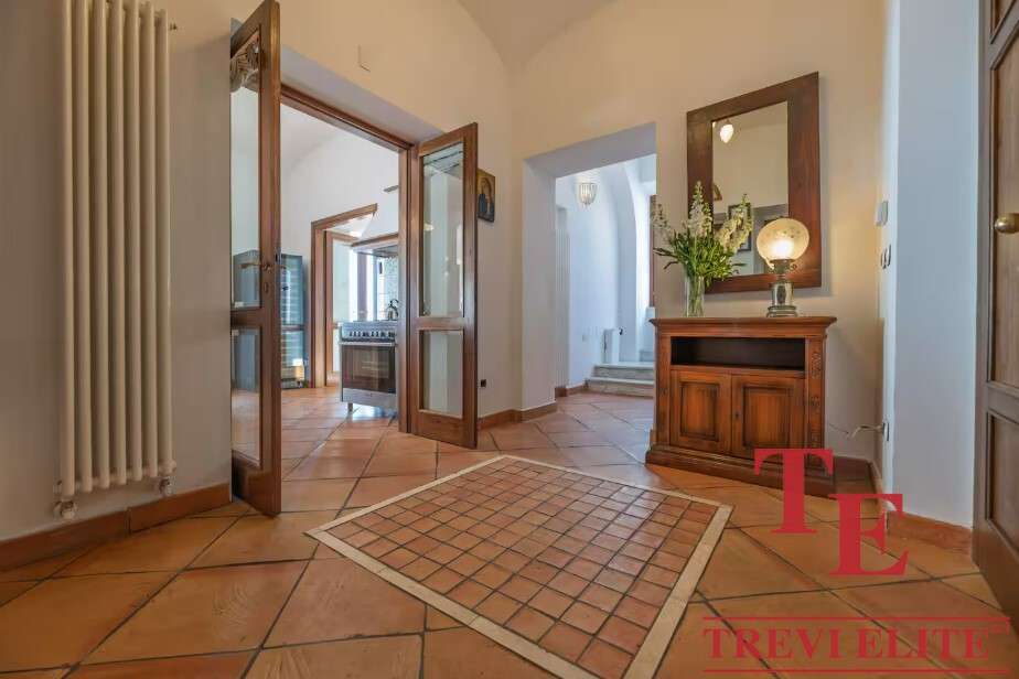 Элегантный интерьер входной зоны с деревянной мебелью и теплой подсветкой, создающий уютную атмосферу в роскошном доме. Идеальное сочетание комфортных и стильных элементов для высокого статуса.