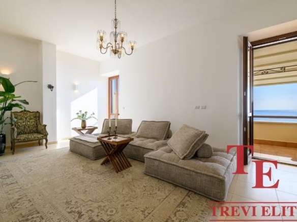 Просторная гостиная с видом на море, светлые стены и уютная мебель, создающая комфорт и элегантность в высококлассной недвижимости.