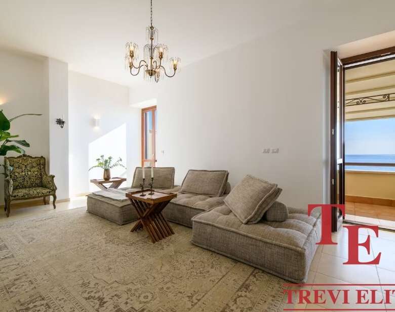 Просторная гостиная с видом на море, светлые стены и уютная мебель, создающая комфорт и элегантность в высококлассной недвижимости.