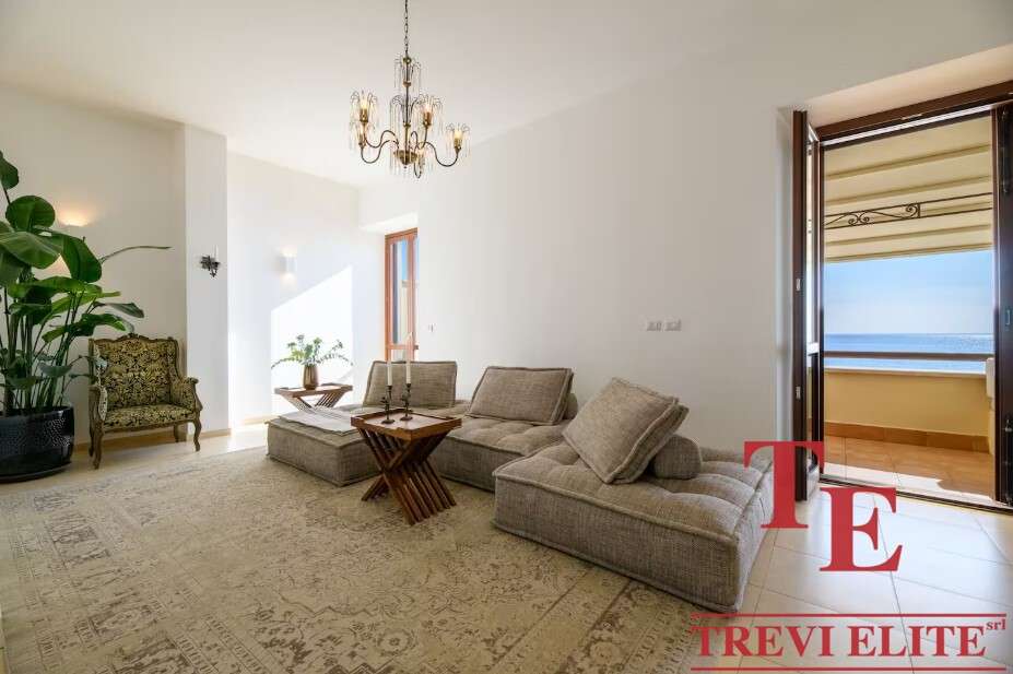 Просторная гостиная с видом на море, светлые стены и уютная мебель, создающая комфорт и элегантность в высококлассной недвижимости.