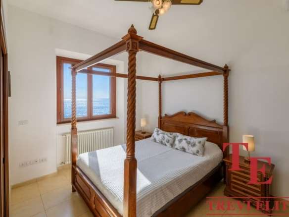 Роскошная спальня с двуспальной кроватью из тикового дерева и панорамным видом на море, созданная для комфортного отдыха и отдыха в элитной недвижимости.