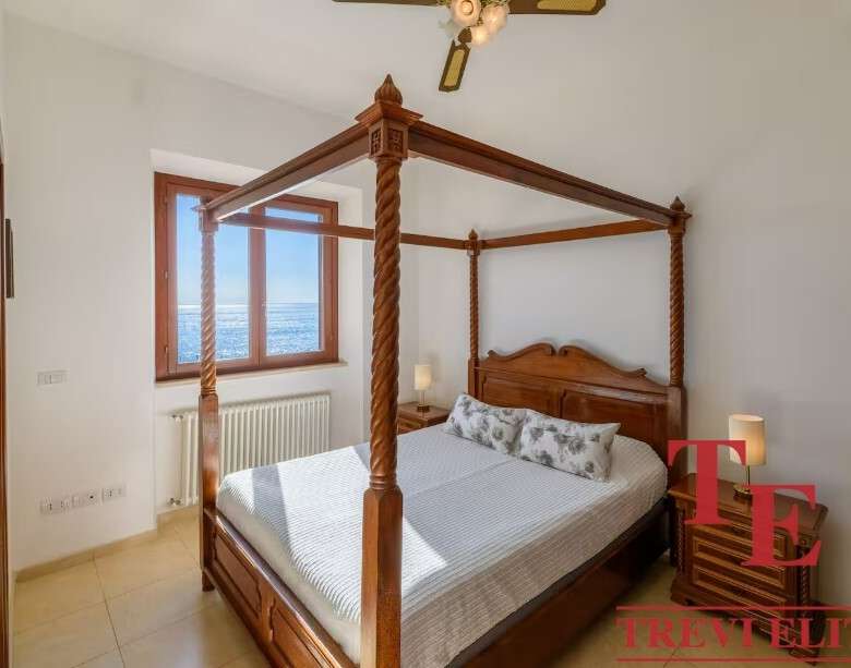 Роскошная спальня с двуспальной кроватью из тикового дерева и панорамным видом на море, созданная для комфортного отдыха и отдыха в элитной недвижимости.