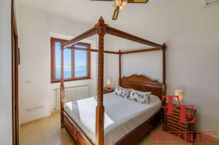 Роскошная спальня с двуспальной кроватью из тикового дерева и панорамным видом на море, созданная для комфортного отдыха и отдыха в элитной недвижимости.