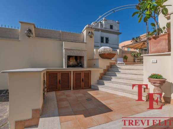 Элитная терраса с зоной для отдыха и камином, стильным декором и мягким освещением, идеальная для эксклюзивных встреч и наслаждения видом в высококлассных итальянских и мировых роскошных недвижимых объектов.