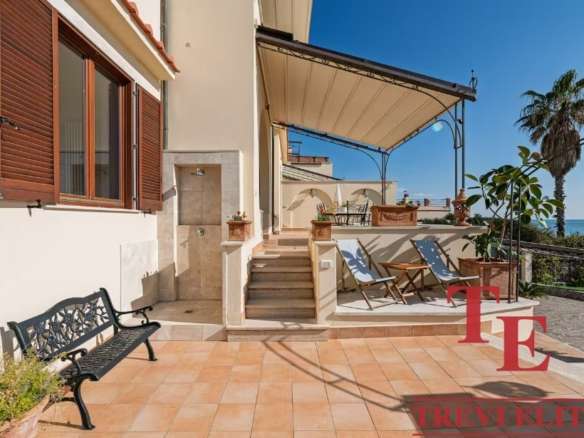 Уютная терраса с видом на море, лаунж-зона и шезлонги для отдыха, окружена пальмами и зеленью, идеальное место для наслаждения морским бризом и солнечными днями.