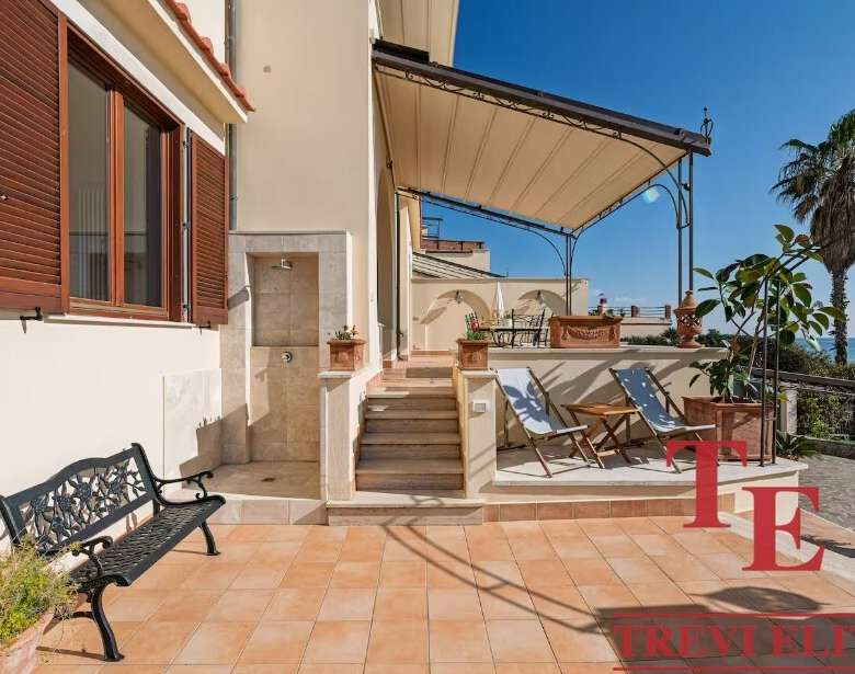 Уютная терраса с видом на море, лаунж-зона и шезлонги для отдыха, окружена пальмами и зеленью, идеальное место для наслаждения морским бризом и солнечными днями.