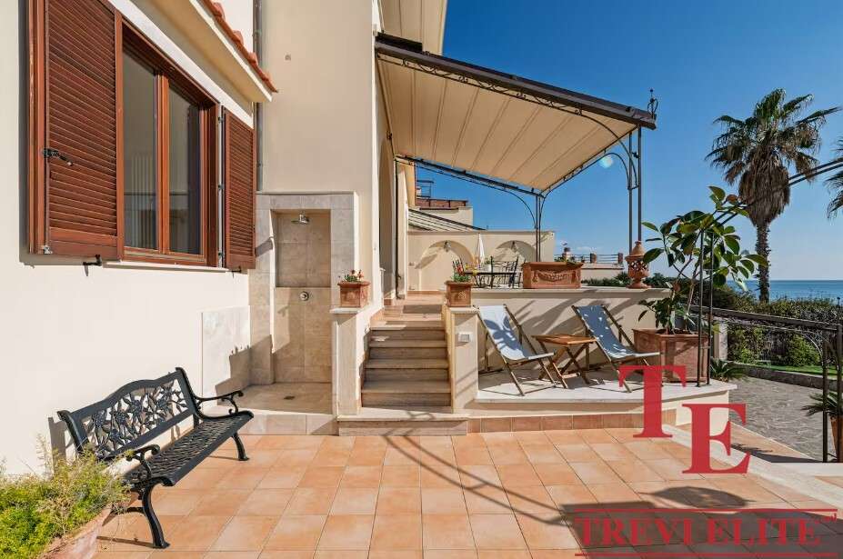 Уютная терраса с видом на море, лаунж-зона и шезлонги для отдыха, окружена пальмами и зеленью, идеальное место для наслаждения морским бризом и солнечными днями.