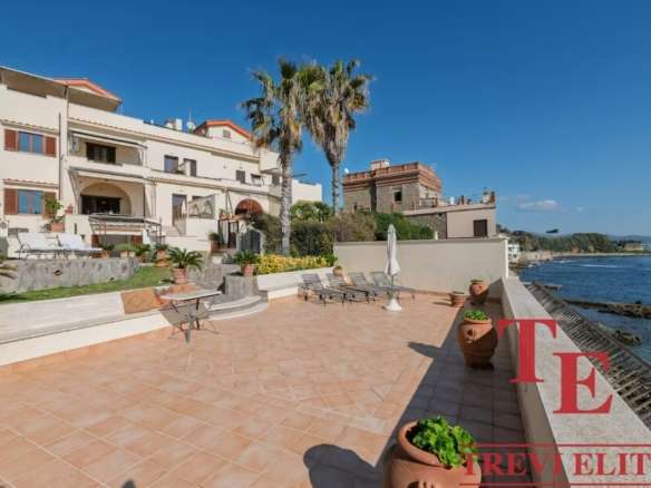 Вид на роскошную виллу у моря с просторной террасой, пальмами и панорамным видом на океан, идеально подходит для элитной недвижимости и роскошных отпуска.