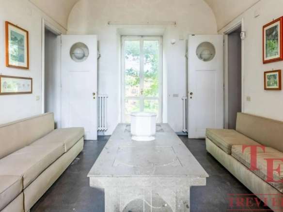 Уютная гостиная с натуральным светом, белыми стенами, двумя длинными диванами и художественными рамками на стенах в классическом стиле. Идеальное место для отдыха в элитном доме.