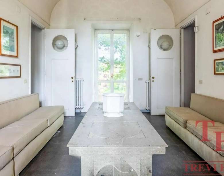 Уютная гостиная с натуральным светом, белыми стенами, двумя длинными диванами и художественными рамками на стенах в классическом стиле. Идеальное место для отдыха в элитном доме.