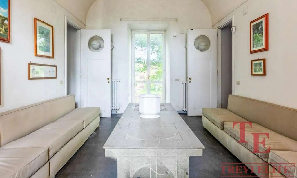 Уютная гостиная с натуральным светом, белыми стенами, двумя длинными диванами и художественными рамками на стенах в классическом стиле. Идеальное место для отдыха в элитном доме.